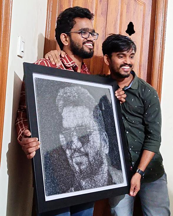 Two friends holding a framed thread portrait