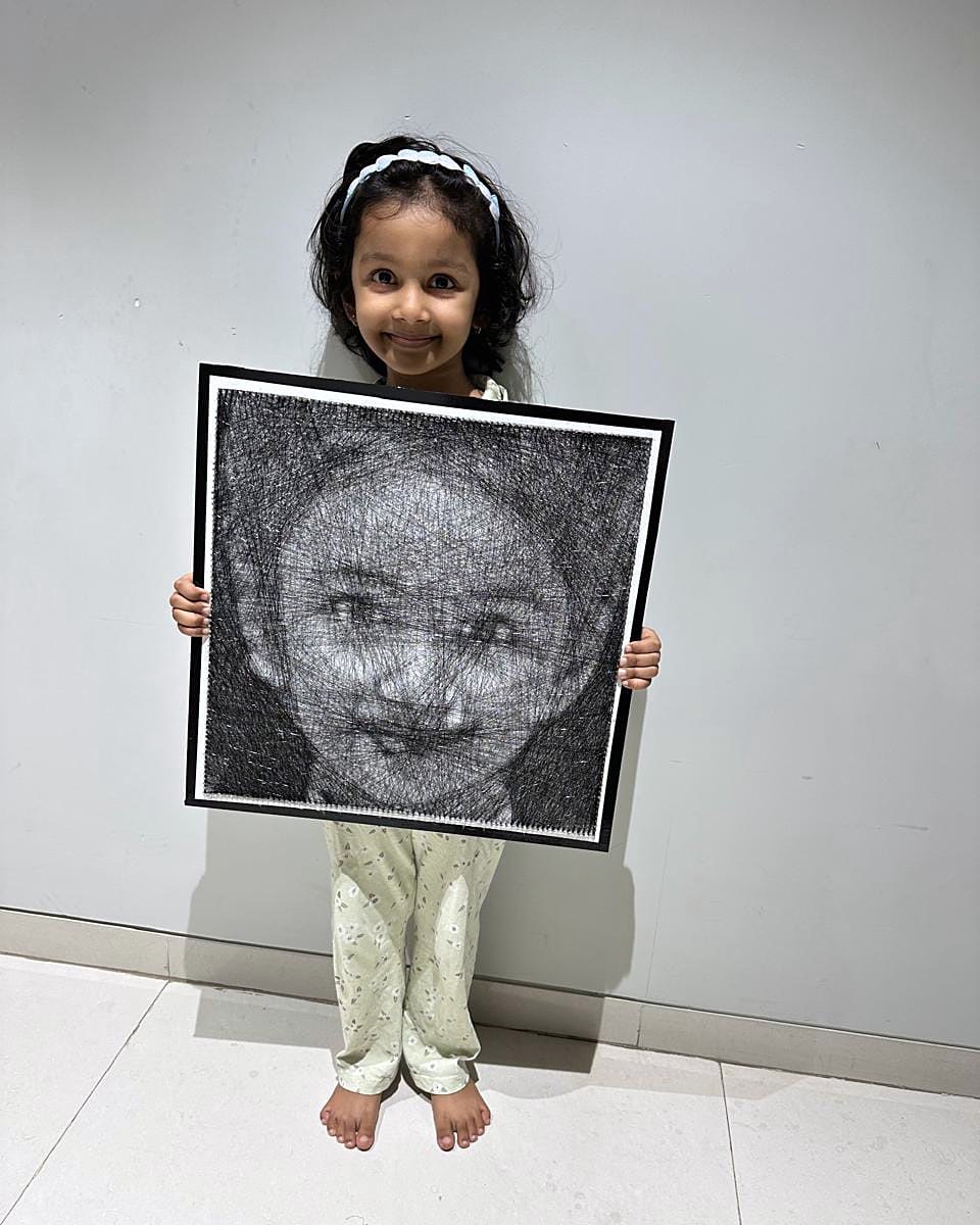 Little girl holding her own framed thread portrait