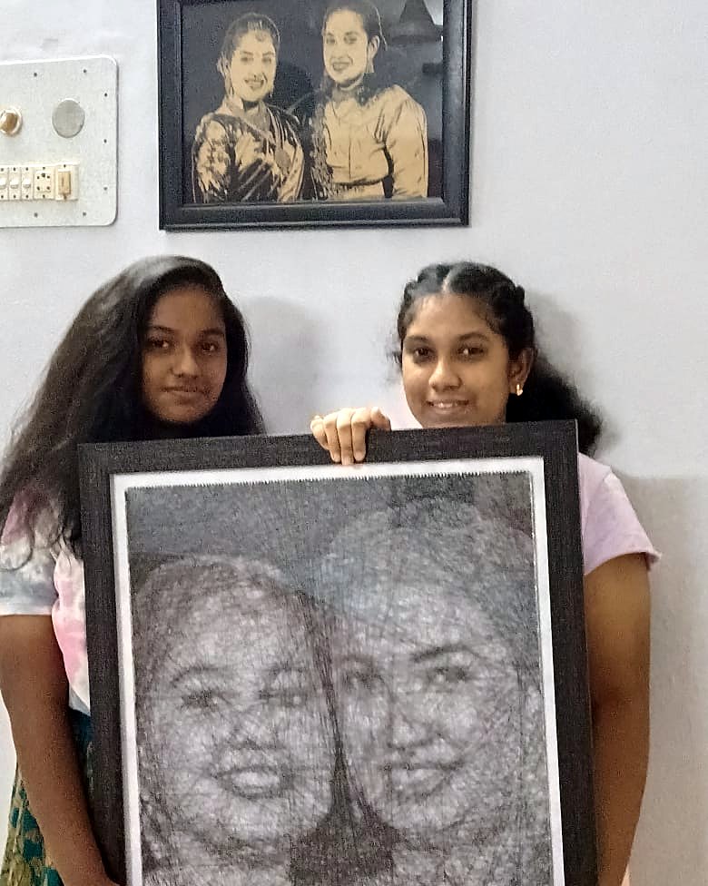 Two girls holding a framed thread portrait of themselves