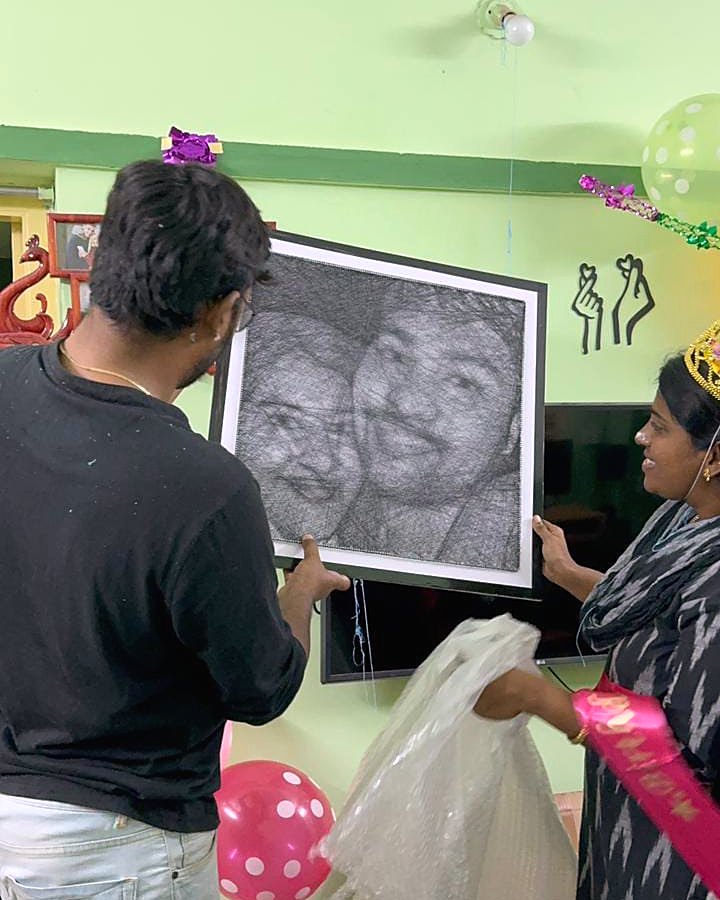 Framed thread portrait unwrapped at a celebration