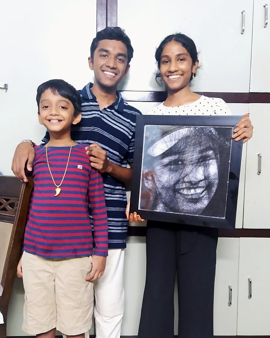 Family holding a framed thread portrait