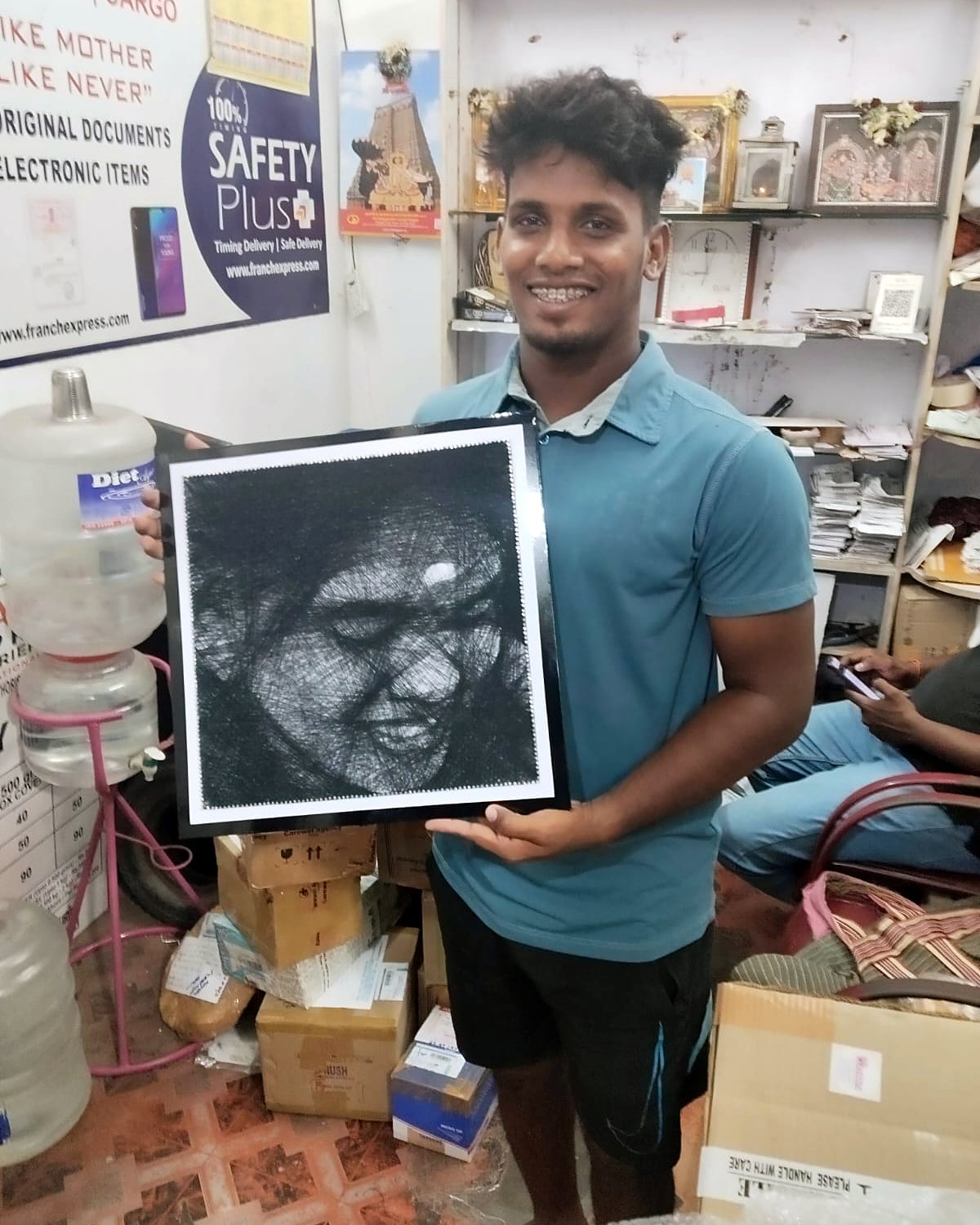 Young man holding a framed thread portrait