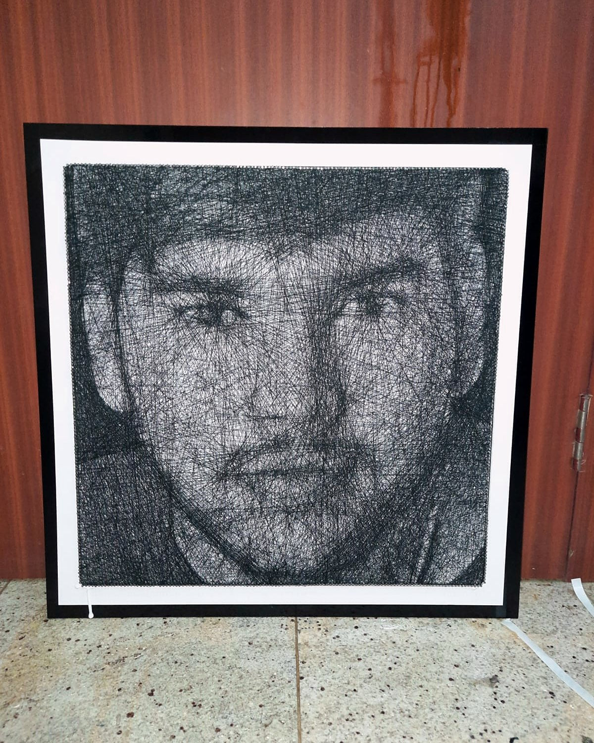 Thread portrait of a young man in a black glass frame