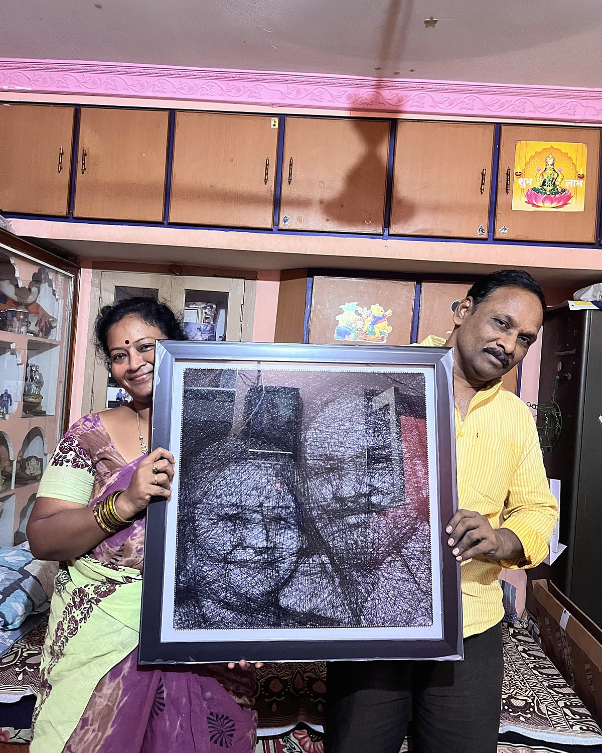 Couple holding a framed thread portrait of themselves