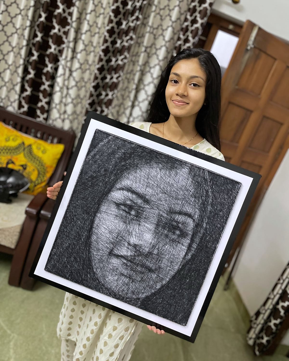 Young woman holding her framed thread portrait